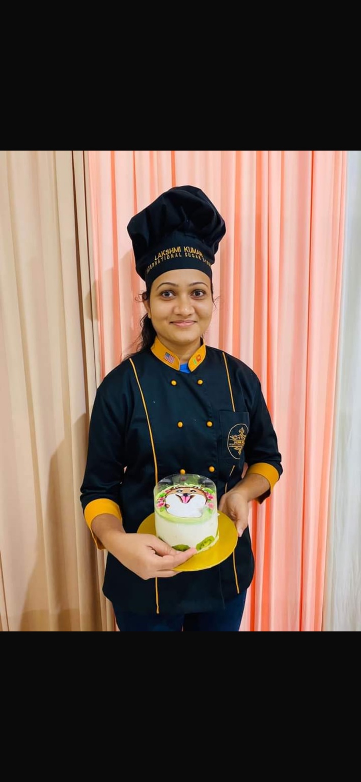 Surangi in her chef uniform holding a decorated cake